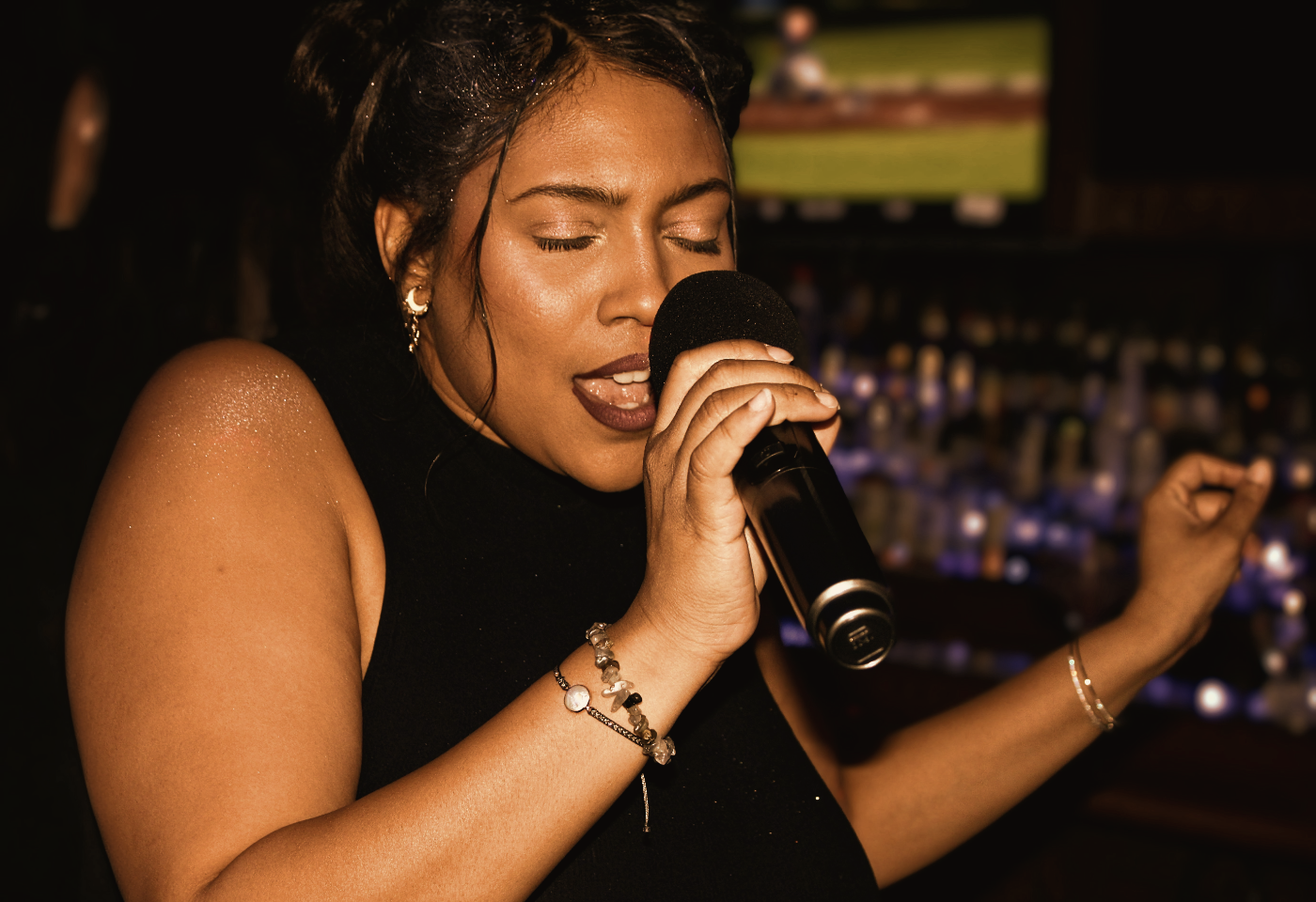 Someone singing into a microphone, eyes closed, warm light